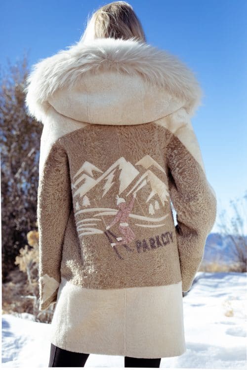 Sheared Mink With Natural Chinchilla Tuxedo Collar on a woman wearing a tan coat with a Park City logo on the back