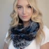 Frontal view of a woman in a blue chinchilla rex fur infinity scarf standing in front of a grey background.