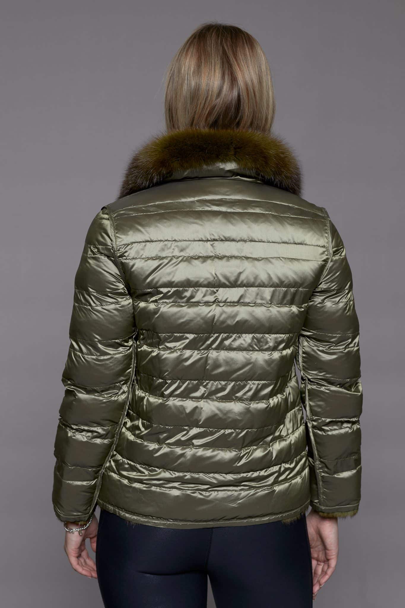 Rear view of a woman wearing a reversible fur coat with the shell side out facing a grey background.