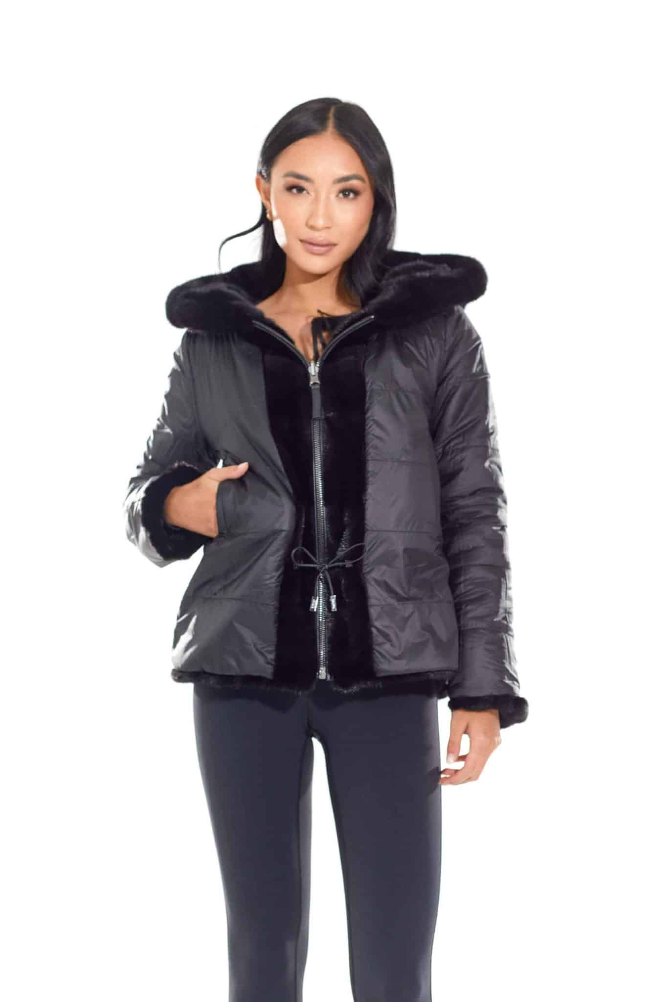 Frontal shot of a woman wearing a mink fur jacket with the rainwear side out standing in front of a white background. The woman's right hand is in the jacket's right pocket.