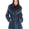 Frontal view of a woman wearing a cross mink fur stroller standing in front of a white background. The woman's hands are in the garment's pockets.