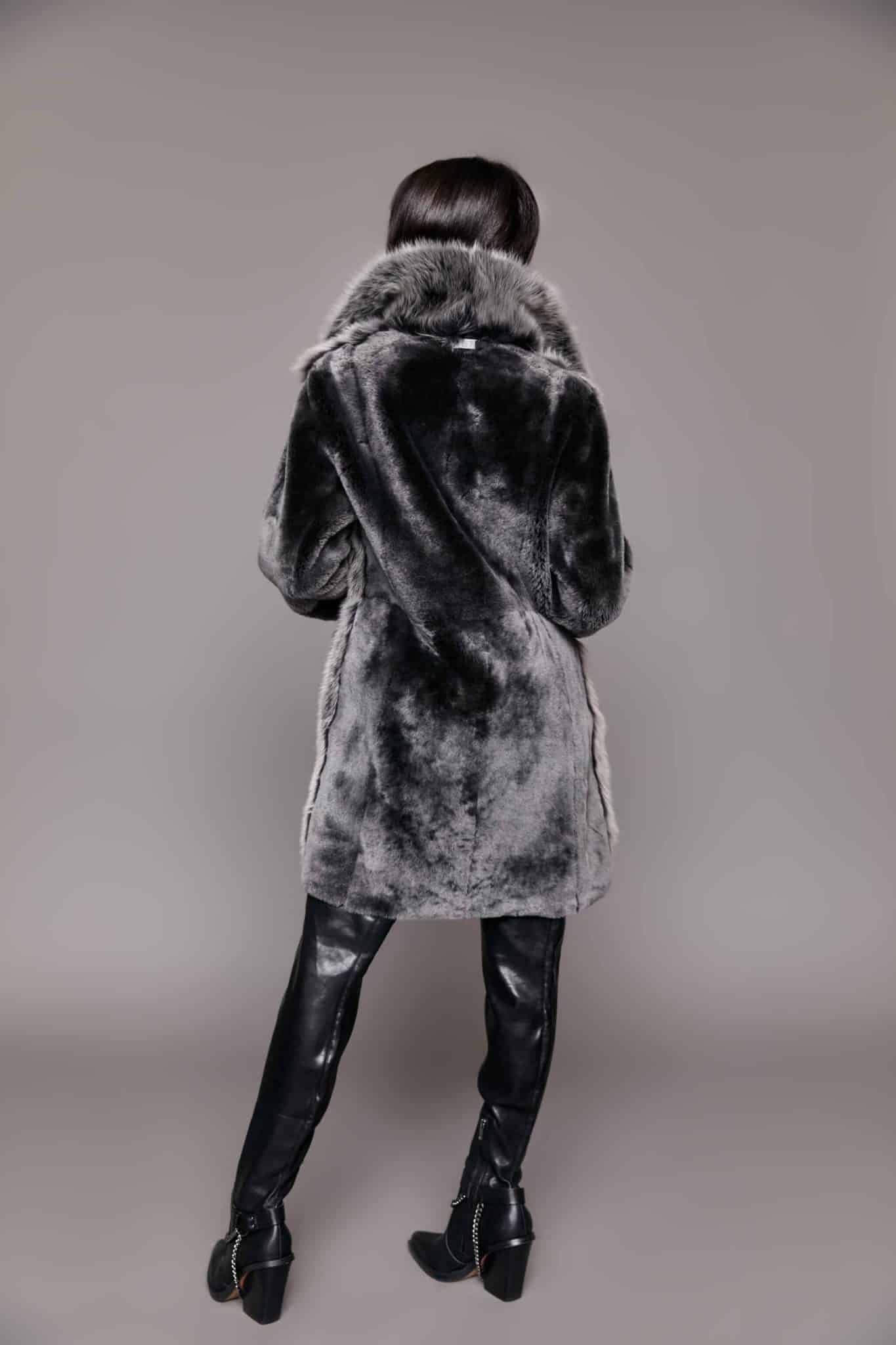 Rear view of a woman wearing a Toscana shearling coat with the fur side out facing a grey background.