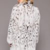 Rear view of a woman wearing a white fur coat turned towards a grey background. The woman's head is turned to the left of frame.