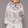 Frontal view of a woman wearing a fur coat standing in front of a grey background