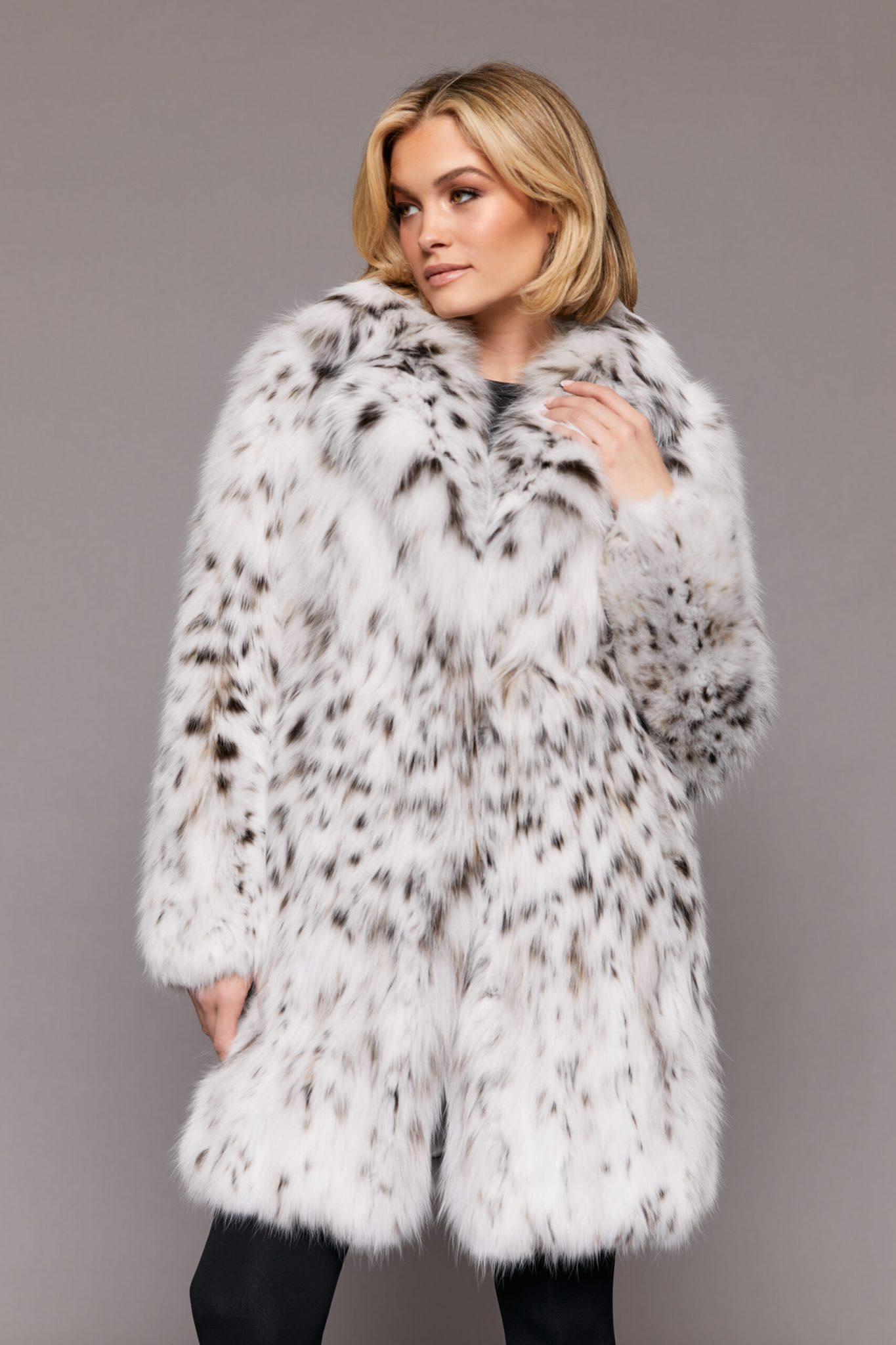 Frontal view of a woman wearing a fur coat standing in front of a grey background