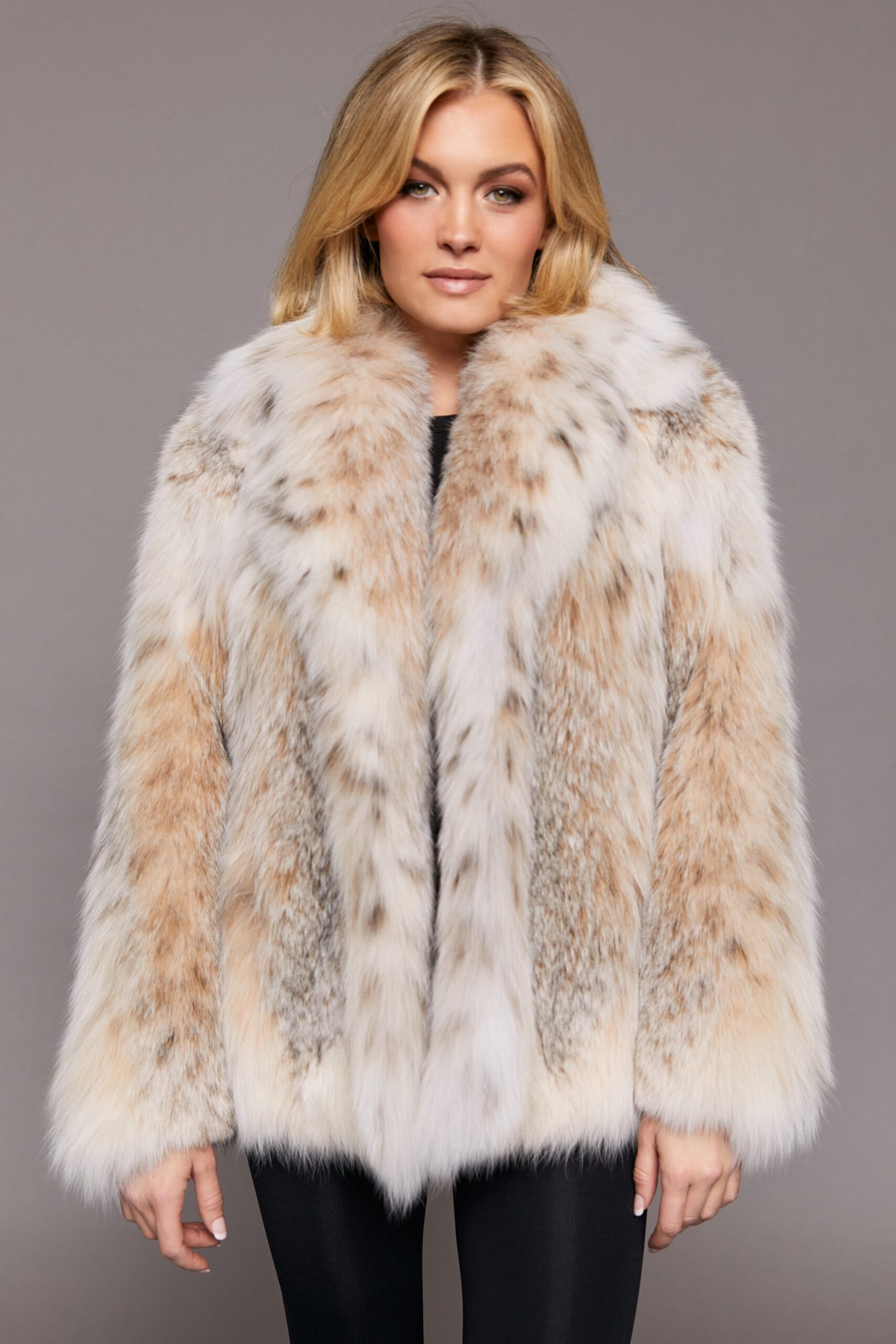Medium shot of a woman wearing a Canadian lynx jacket standing in front of a grey backdrop