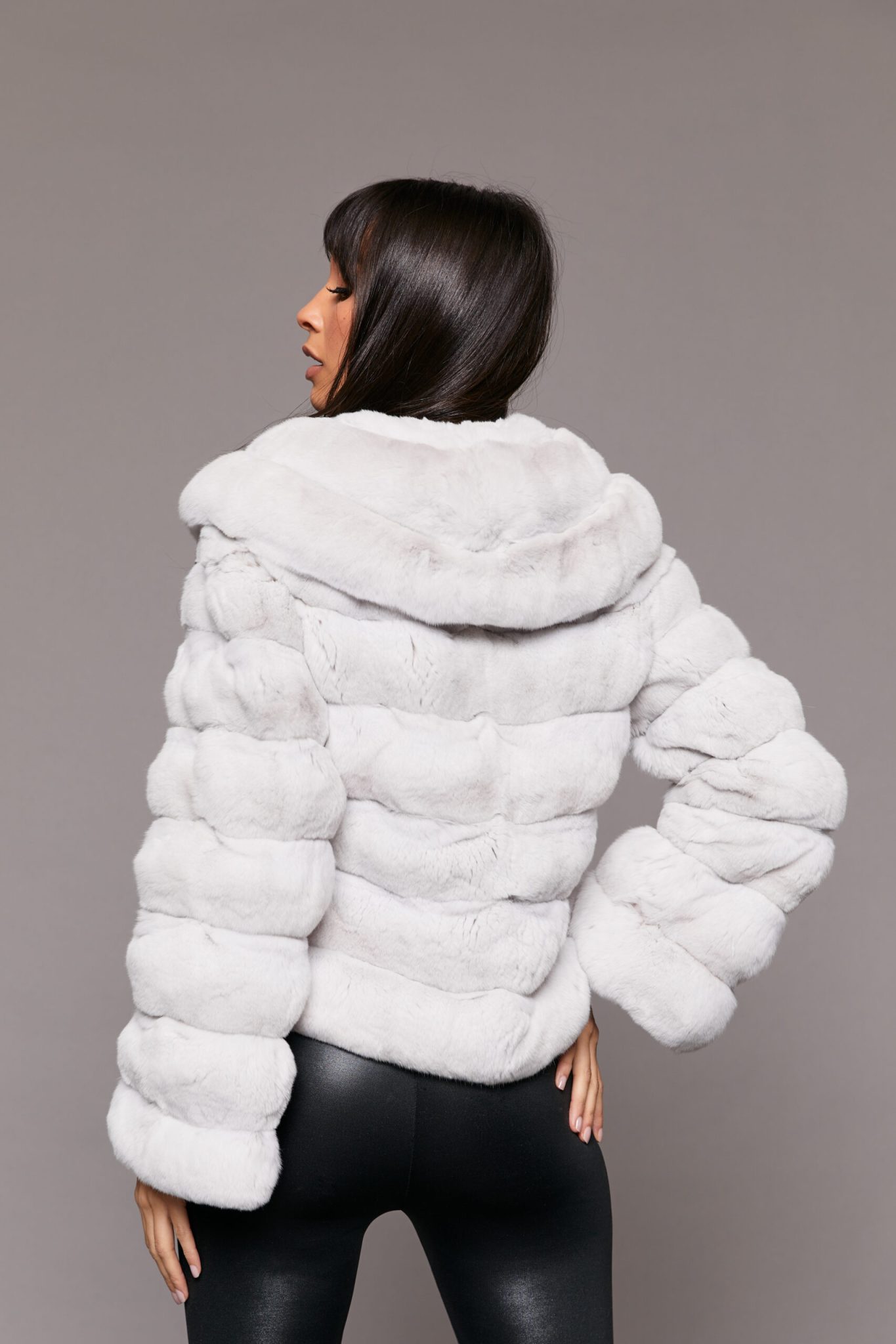 Rear view of a woman wearing a white Erato Chinchilla Jacket with Shawl Collar standing in front of a seamless backdrop