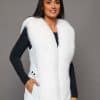 SFGPHOTOPIADAY1_LOOK40_0104 Frontal view of a woman in a white fox pelt vest standing in front of a grey background
