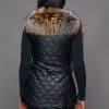 SFGPHOTOPIADAY1_LOOK40_0108 Rear view of a woman in a crystal fox pelt vest facing a grey background
