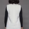 Rear view of a woman in a white mink fur vest facing a grey background