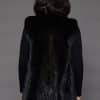 Rear view of a woman in a black mink fur vest facing a grey background