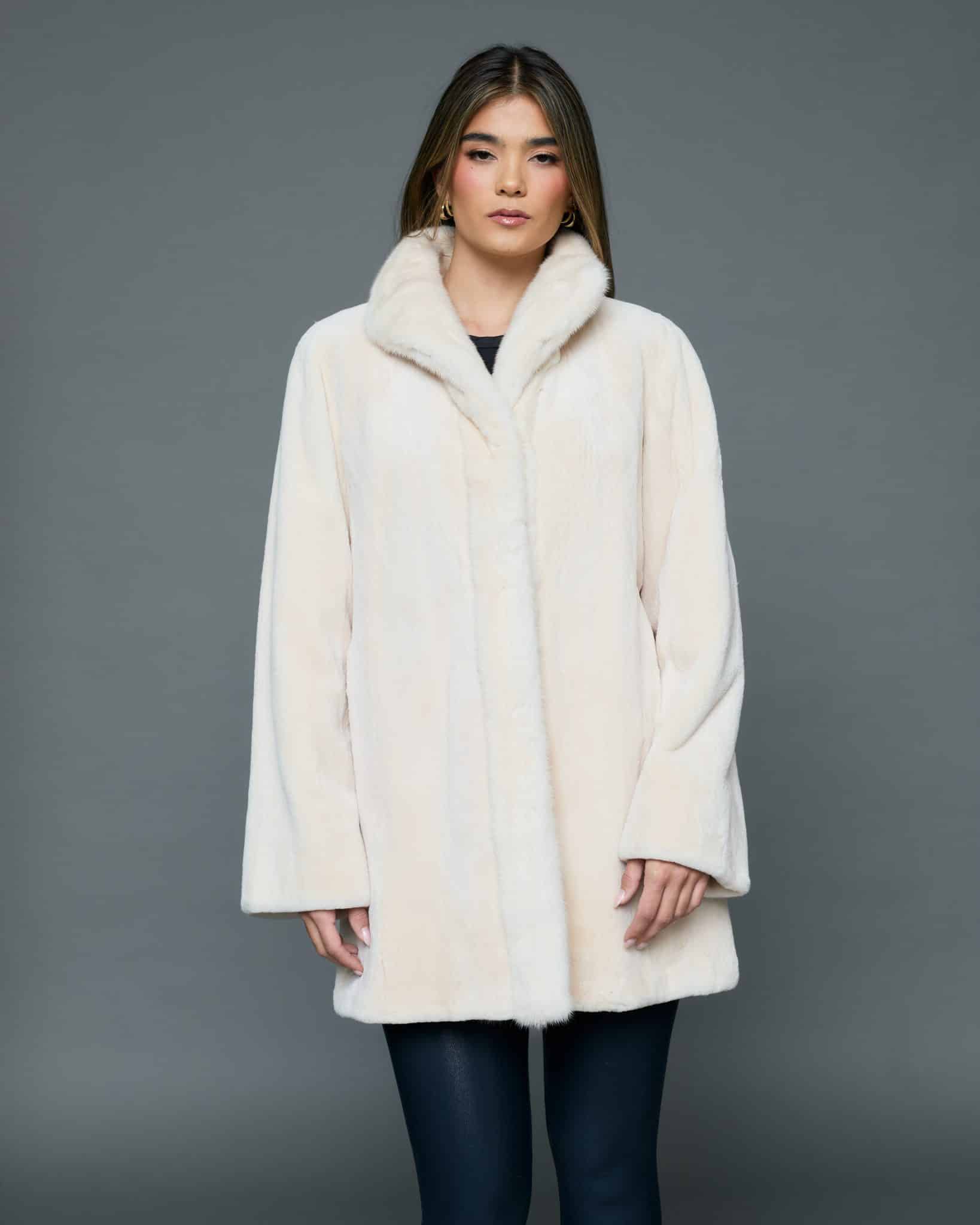 ECOMMWOMENS20256616 Frontal view of a woman in a white coat with the fur side out standing in front of a grey background