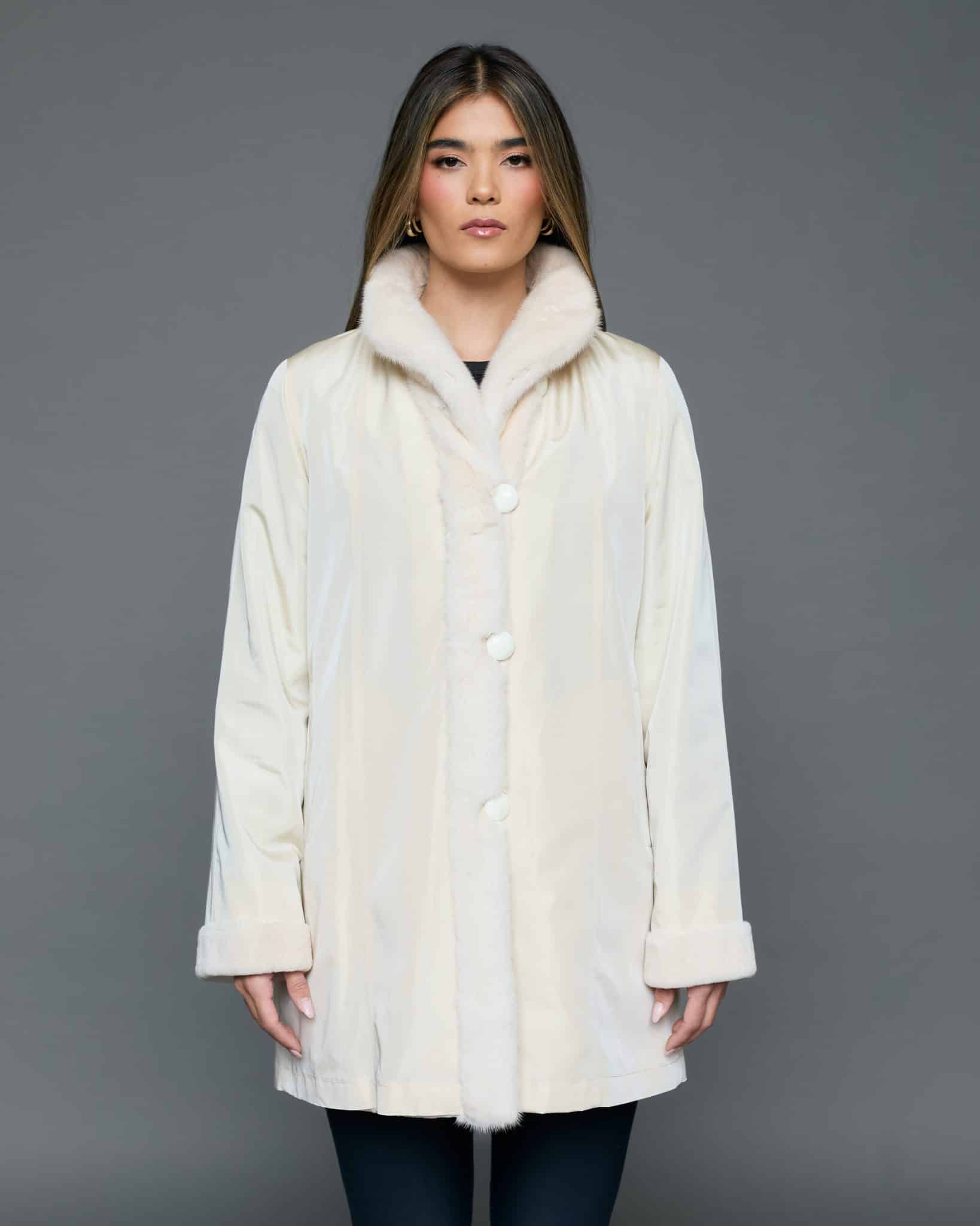 ECOMMWOMENS20256972 Medium frontal view of a woman in a white coat with the fur side out standing in front of a grey background