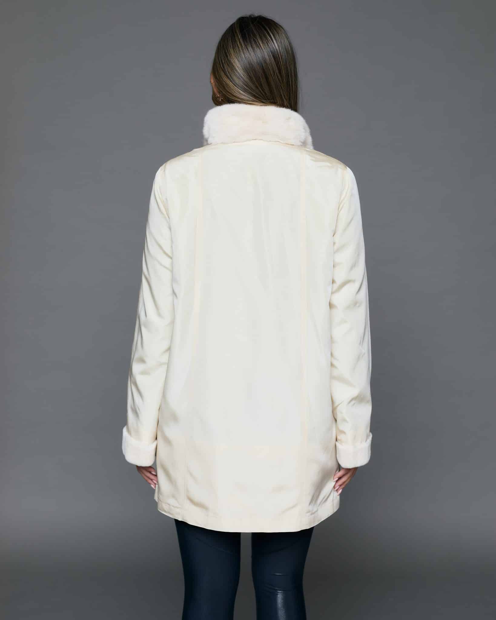 ECOMMWOMENS20256977 Rear view of a woman in a white coat with the fur side out facing a grey background