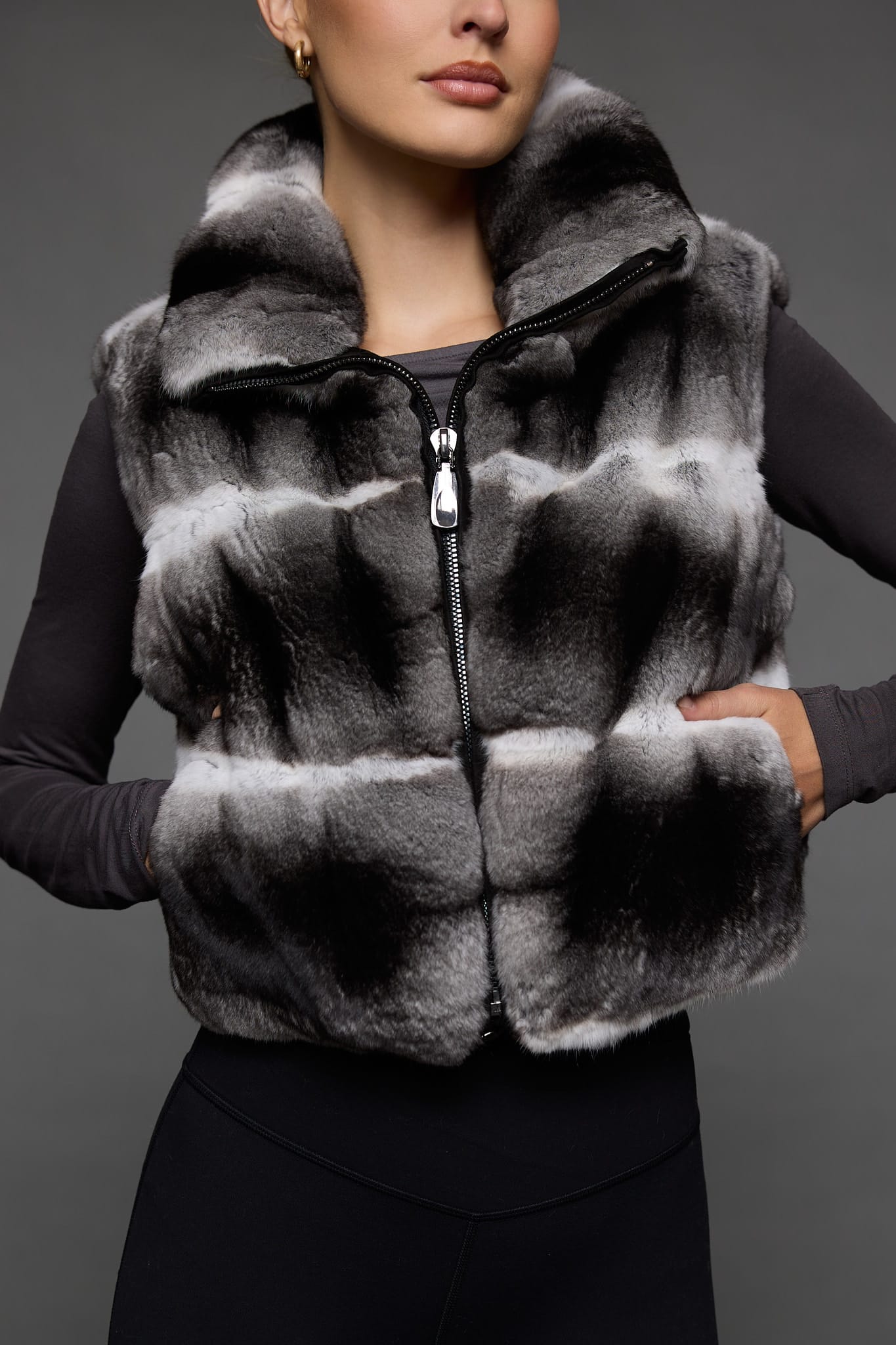 up close image of a woman in a grey vest against a grey wall