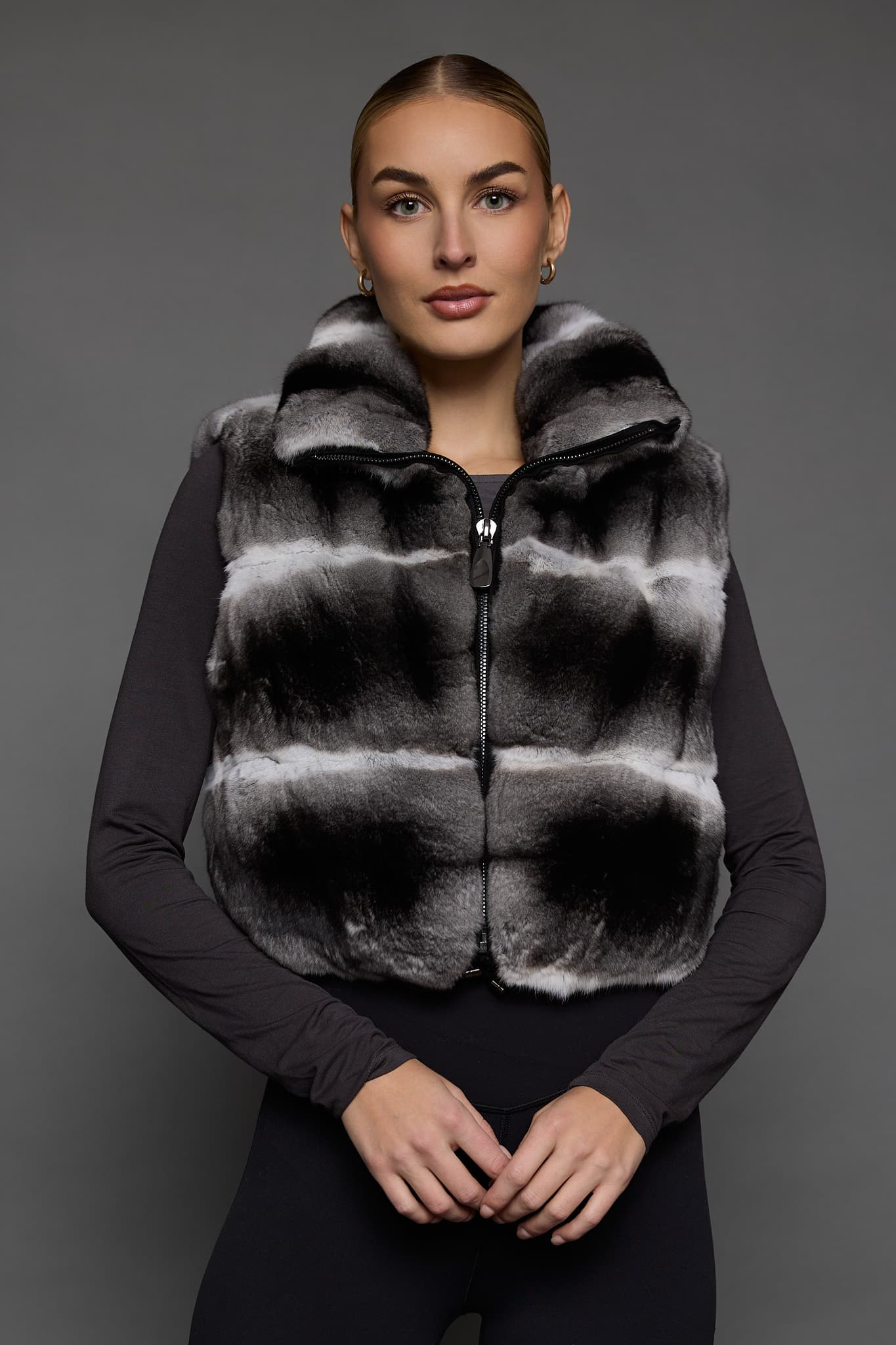 woman in a grey vest against a grey wall