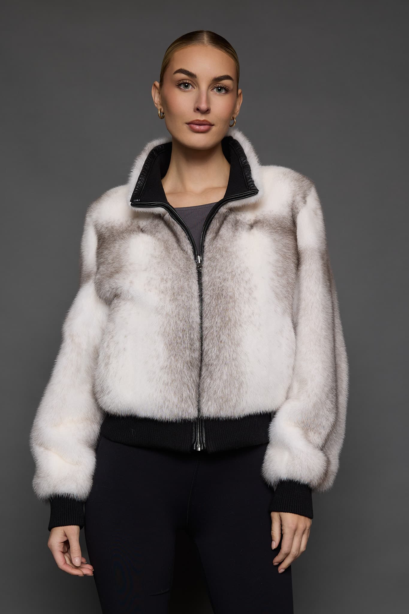 Frontal view of a woman in a white jacket against a grey background
