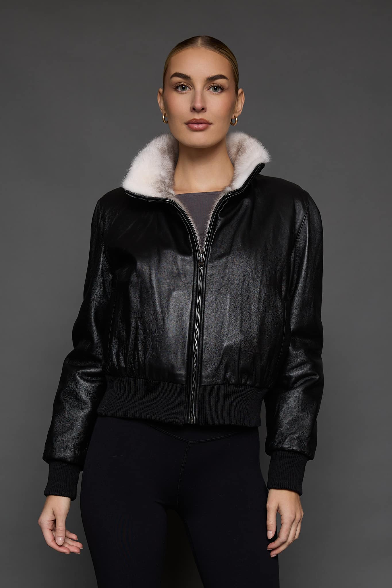 ATHANASIA CROSS MINK JACKET REV FRONT woman in a black leather jacket against a grey background