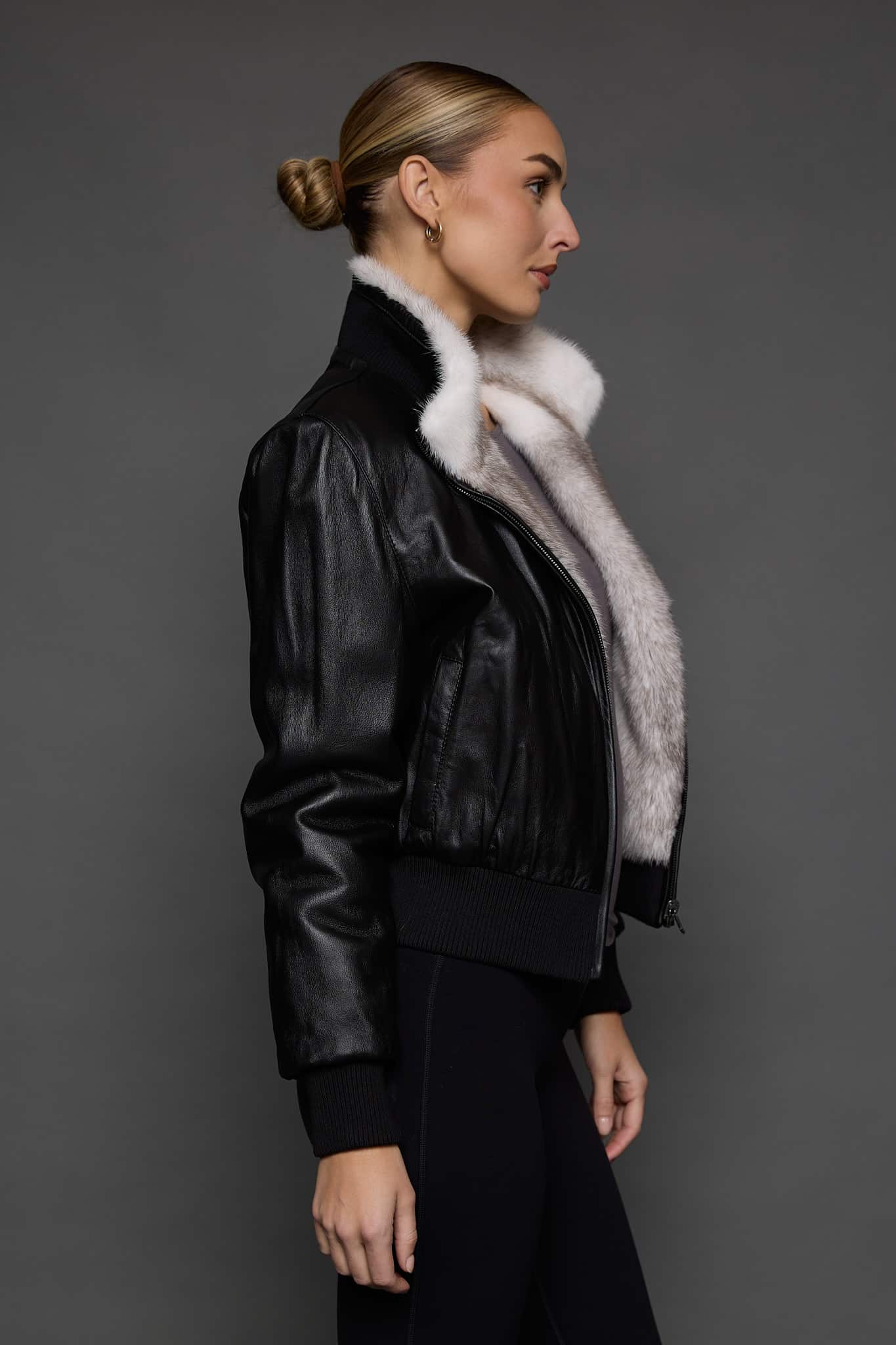 ATHANASIA CROSS MINK JACKET REV SIDE the side of a woman in a black leather jacket against a grey background