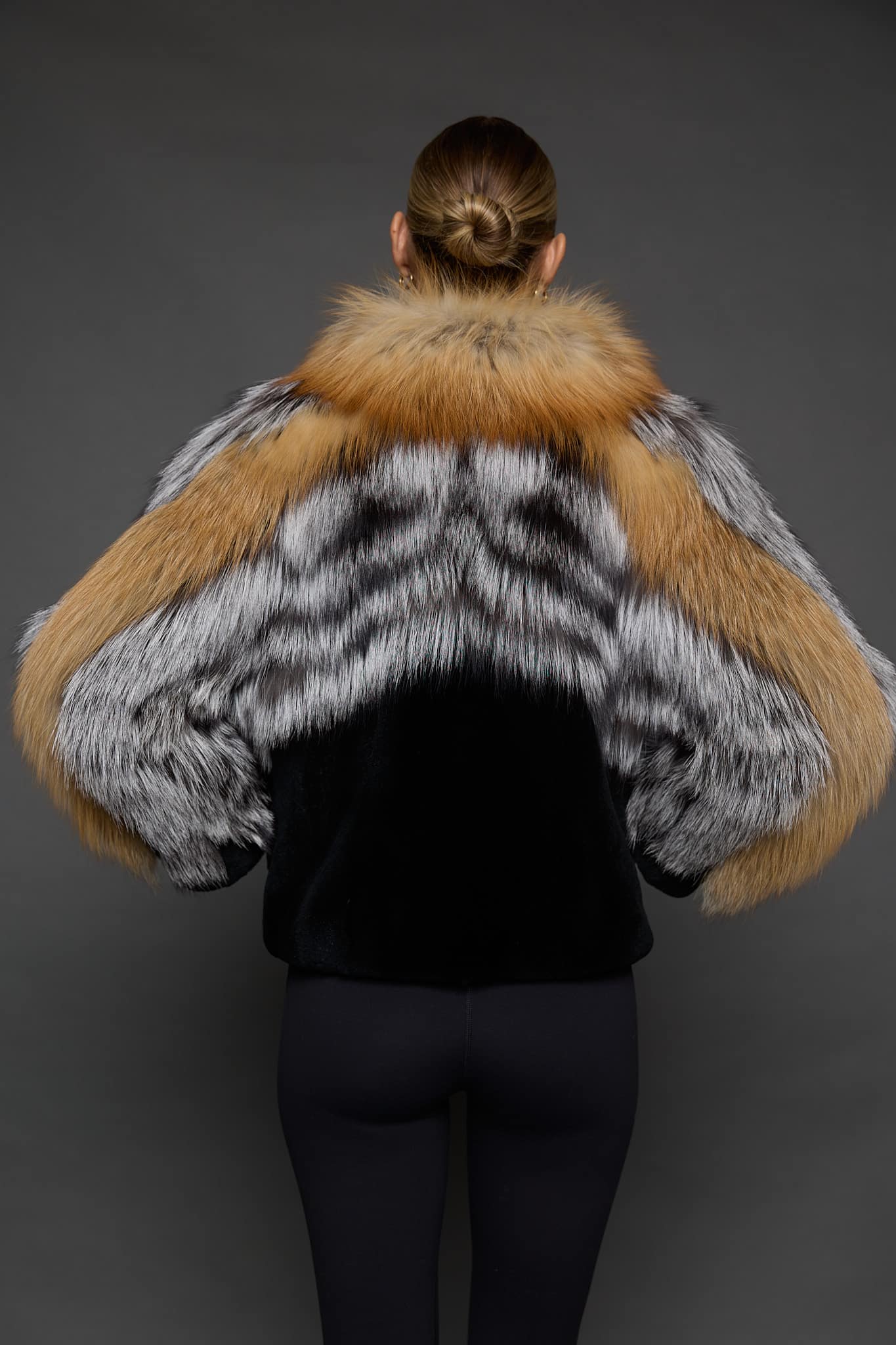CAMILLA RED FOX JACKET BACK the back of a woman in a red and black jacket with her hands on her waist against a grey background