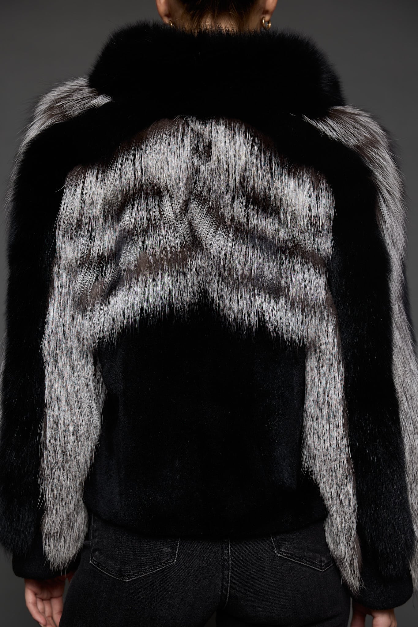 CAMILLA SILVER FOX JACKET BACK the back of a woman in a silver and black jacket against a grey background