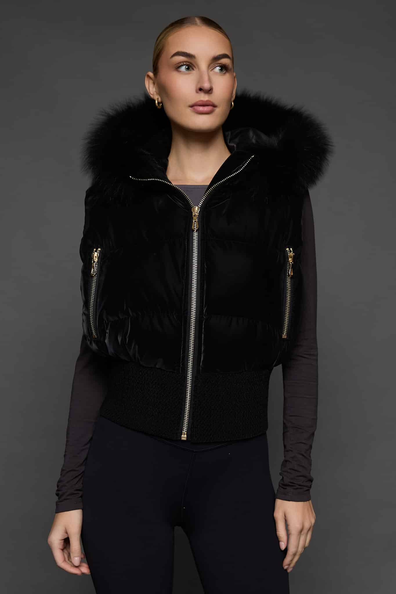 woman in a black vest against a grey background