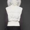the back of a woman in a white vest against a grey background