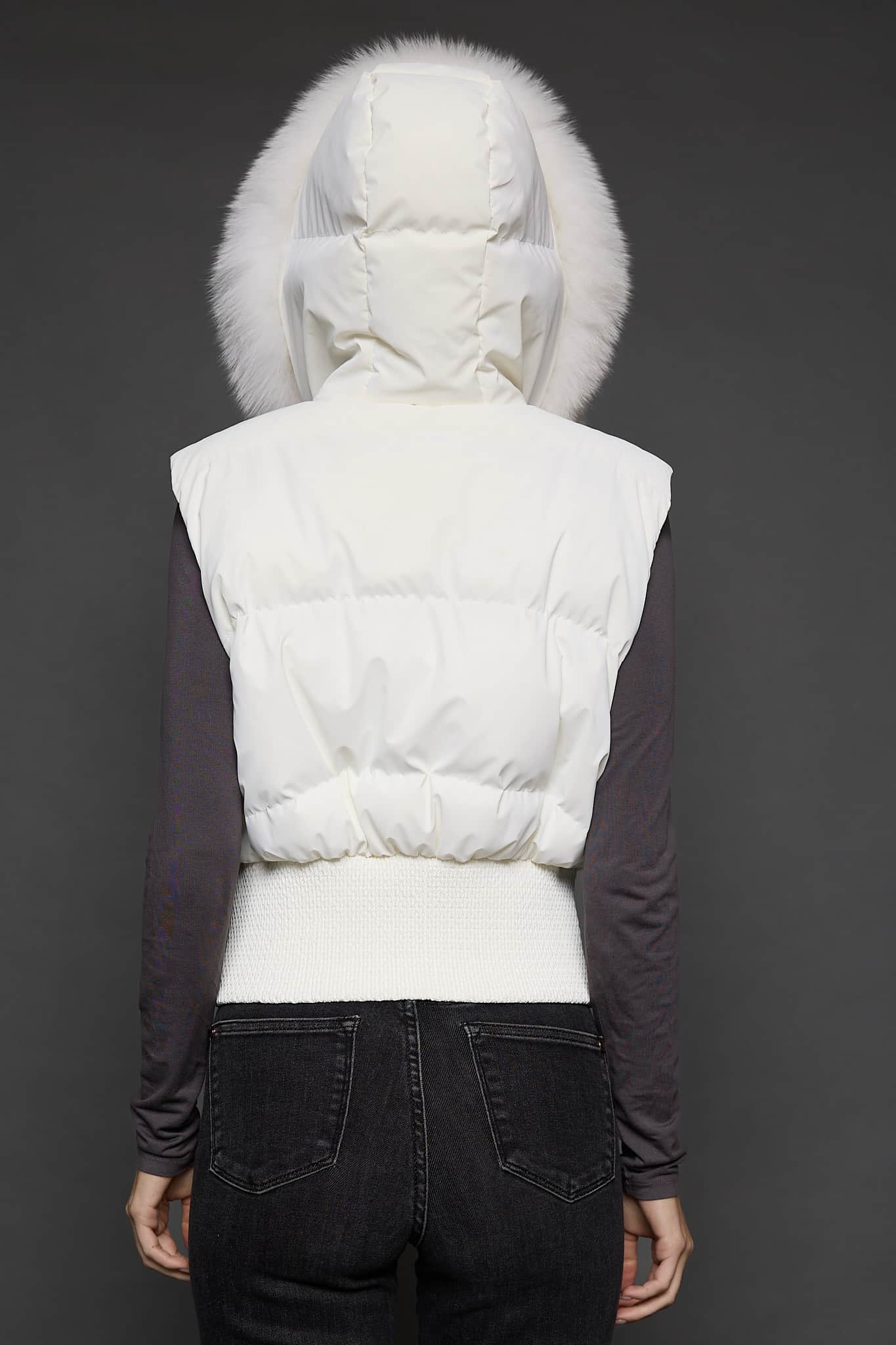 the back of a woman in a white vest against a grey background