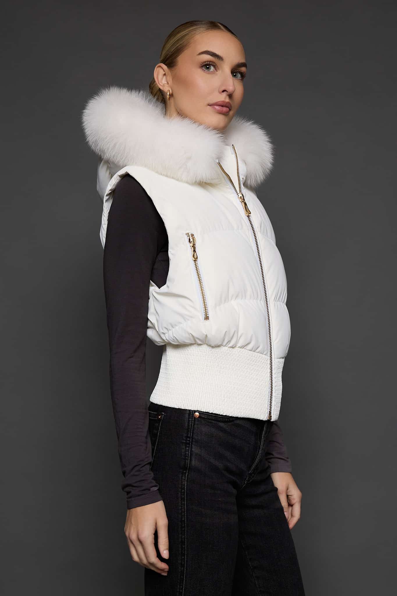 the side of a woman in a white vest against a grey background