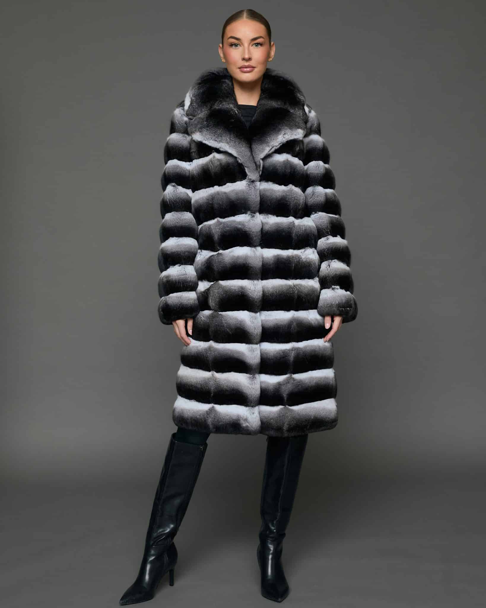 ECOMMWOMENS20255567 Frontal view of a woman in a natural empress chinchilla coat with her arms at her side standing in front of a grey background.