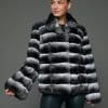ECOMMWOMENS20255638 Frontal view of a woman in a natural chinchilla jacket with wing collar standing in front of a grey background