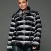 ECOMMWOMENS20255640 Frontal view of a woman in a natural black and white chinchilla jacket with her arms at her sides standing in front of a grey background