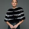 Frontal view of a woman in a natural chinchilla stole / cape with her hands together standing in front of a grey background