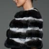 Profile shot of a woman in a natural chinchilla stole / cape standing in front of a grey background