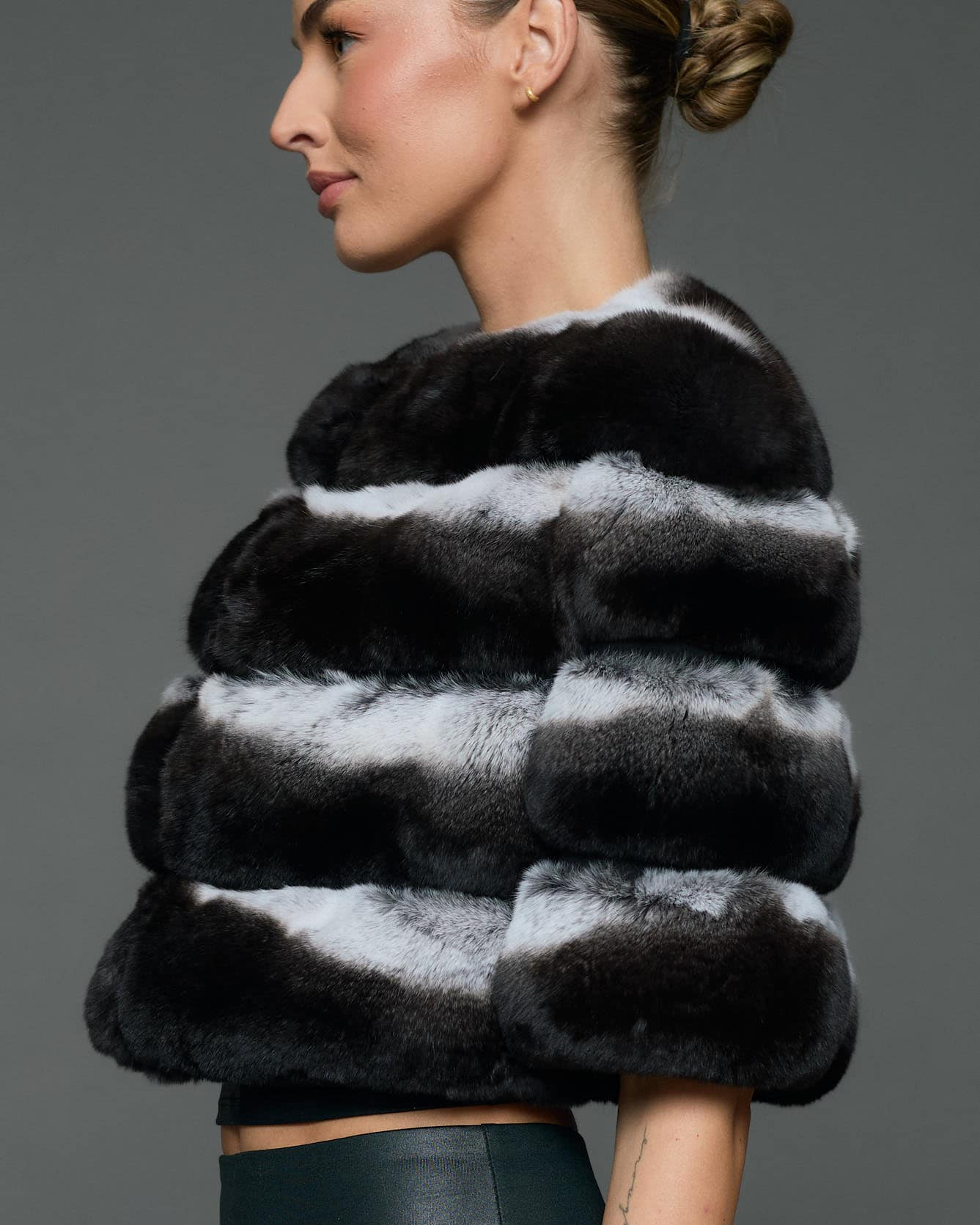 Profile shot of a woman in a natural chinchilla stole / cape standing in front of a grey background