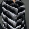 Close-up view of a knee-length black and white chinchilla vest in front of a grey background