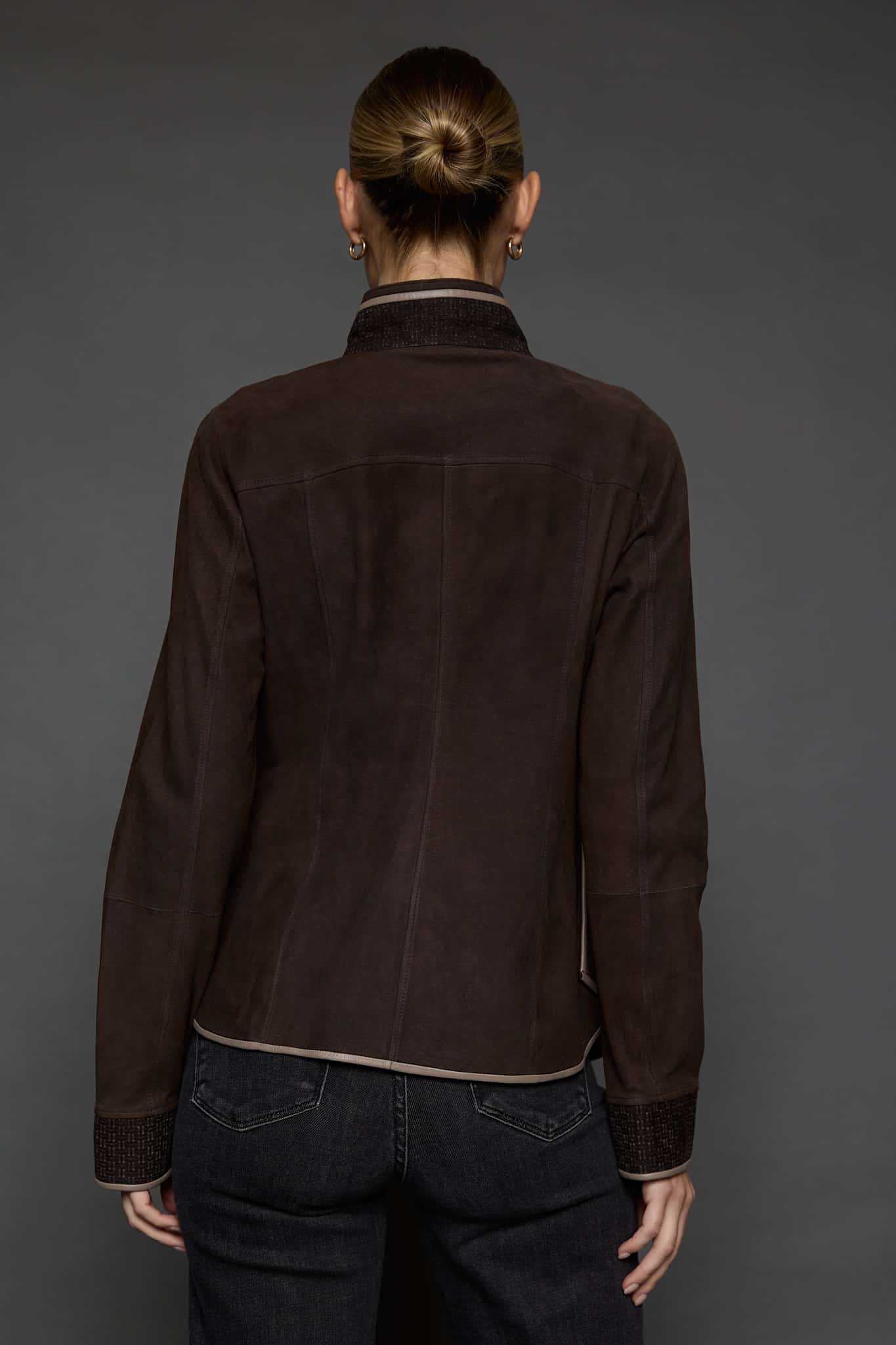 IMANI BROWN TAN JACKET BACK the back of woman in a dark brown jacket against a grey background