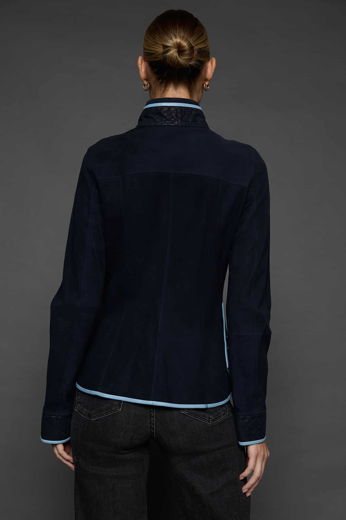 IMANI NAVY BLUE JACKET BACK the back of a woman in a dark blue jacket against a grey background