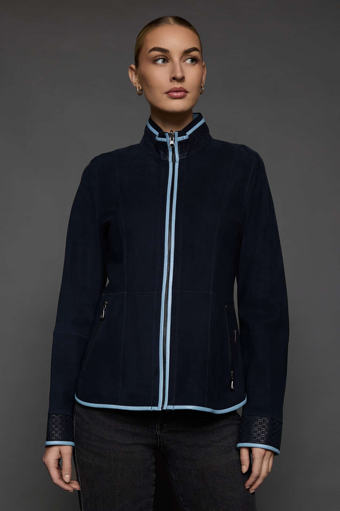woman in a dark blue jacket against a grey background