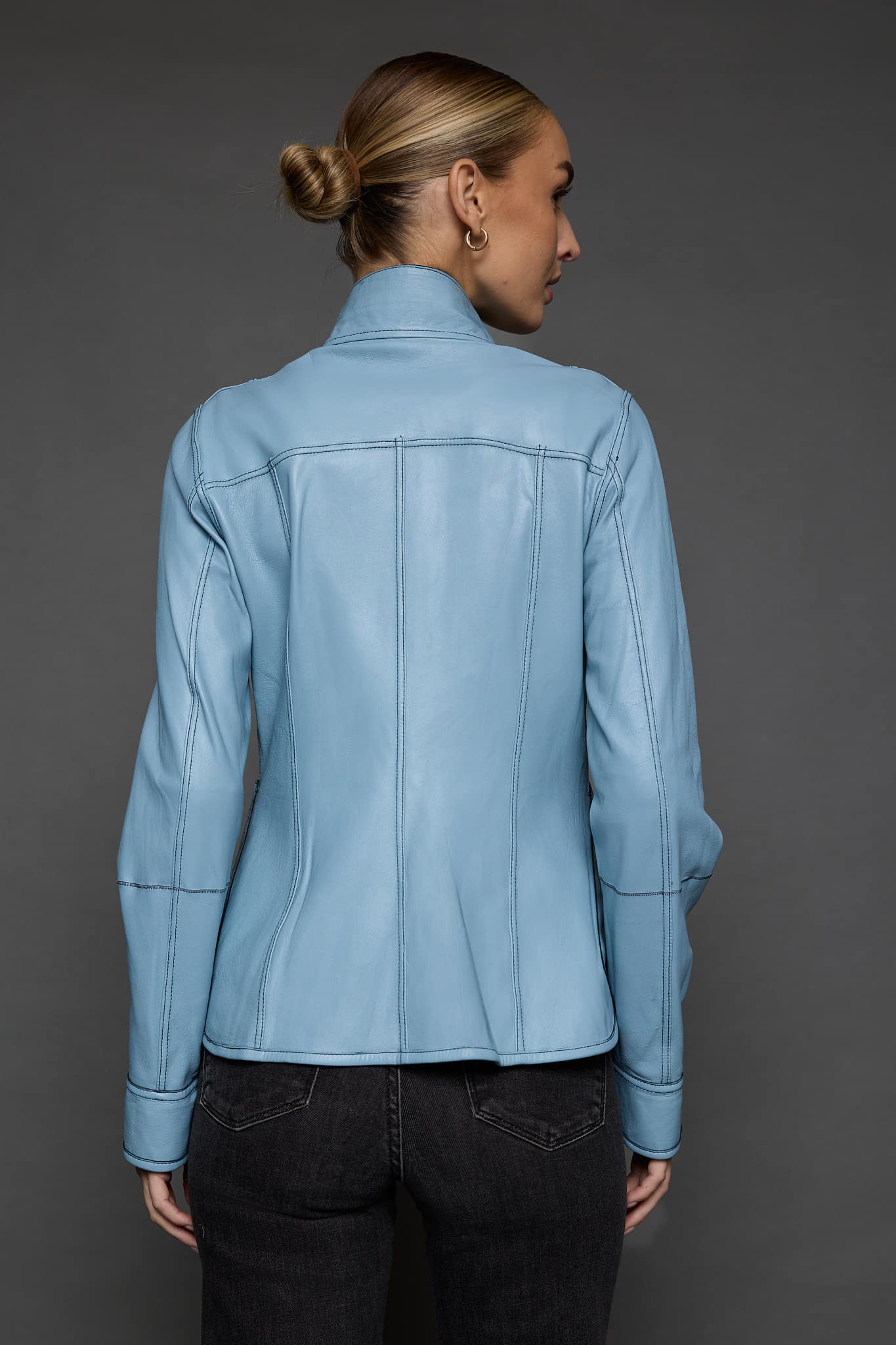 IMANI NAVY BLUE JACKET REV BACK the back of a woman in a light blue jacket against a grey background