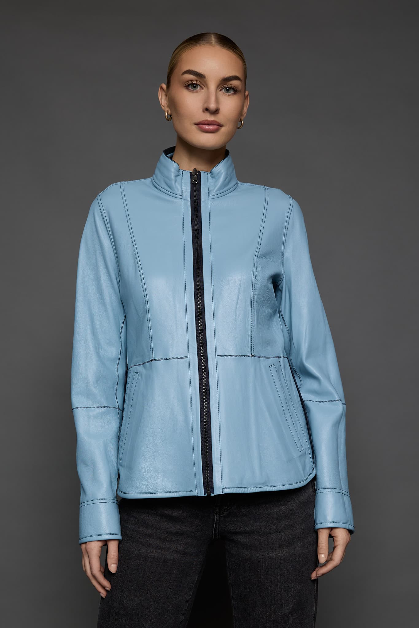 IMANI NAVY BLUE JACKET REV FRONT woman in a light blue jacket against a grey background
