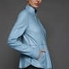 IMANI NAVY BLUE JACKET REV SIDE the side of a woman in a light blue jacket against a grey background