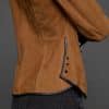 IMANI SNUFF BLACK JACKET DETAIL close up of the waist of a woman in a tan jacket against a grey background
