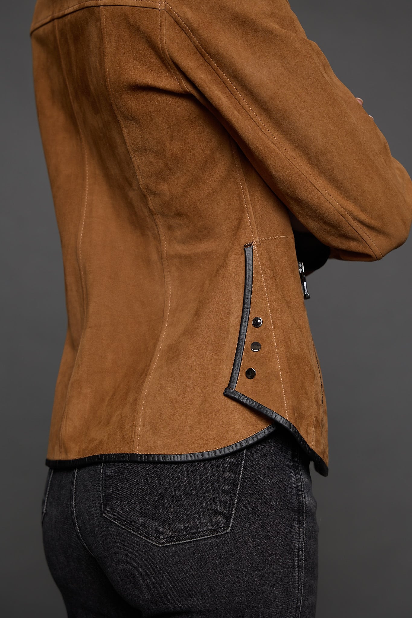 IMANI SNUFF BLACK JACKET DETAIL close up of the waist of a woman in a tan jacket against a grey background