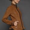 IMANI SNUFF BLACK JACKET SIDE the side of a woman in a tan jacket against a grey background