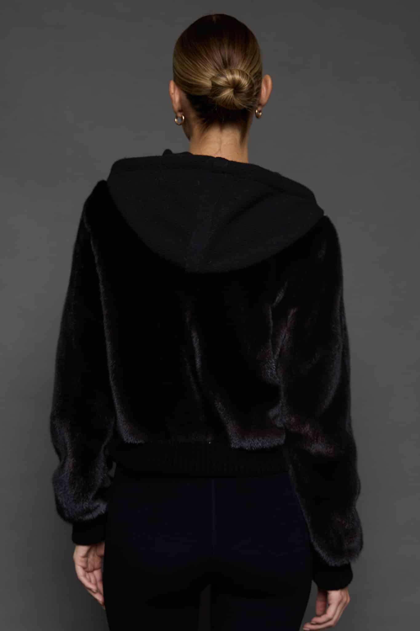 the back of a woman in a black jacket against a white background