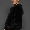 the side of a woman in a black jacket against a white background