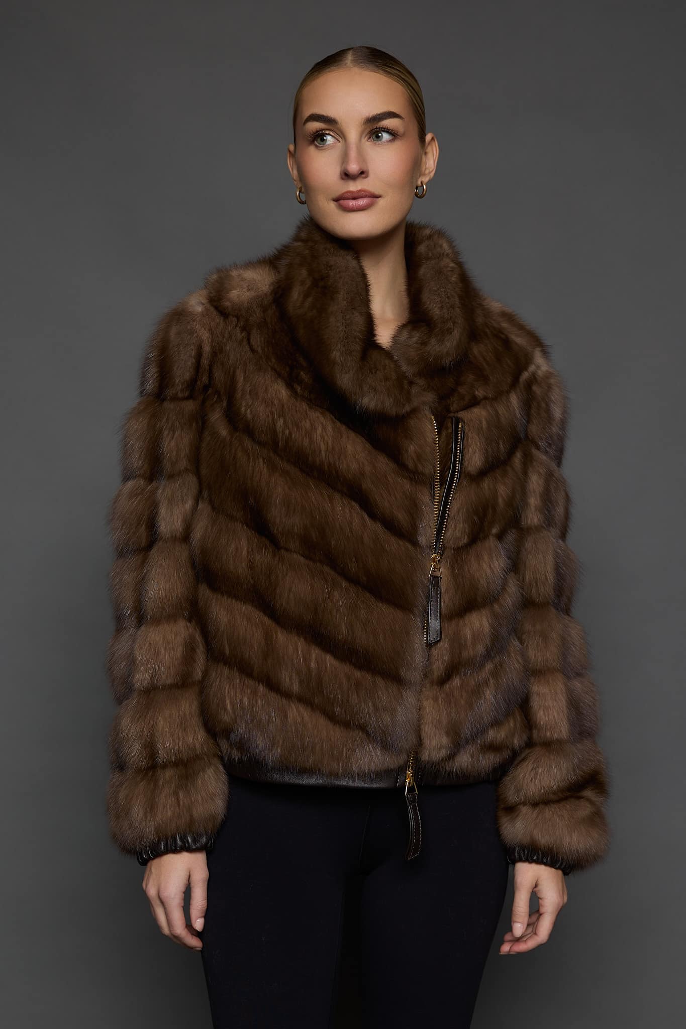 Front view of a woman in a Russian sable jacket standing in front of a dark grey background