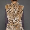 Rear view of a woman in a sculpted American lynx vest with her hands at her side, standing in front of a grey background