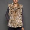 Frontal view of a woman in a sculpted American lynx vest with her right hand in the front pocket, standing in front of a grey background